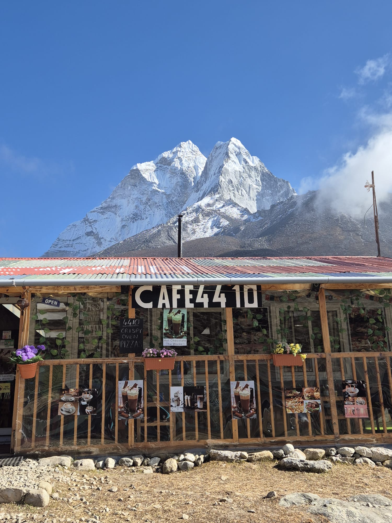 Cafe 4410 along the Everest Base Camp trail, with trekkers resting outside and panoramic mountain views in the background.
