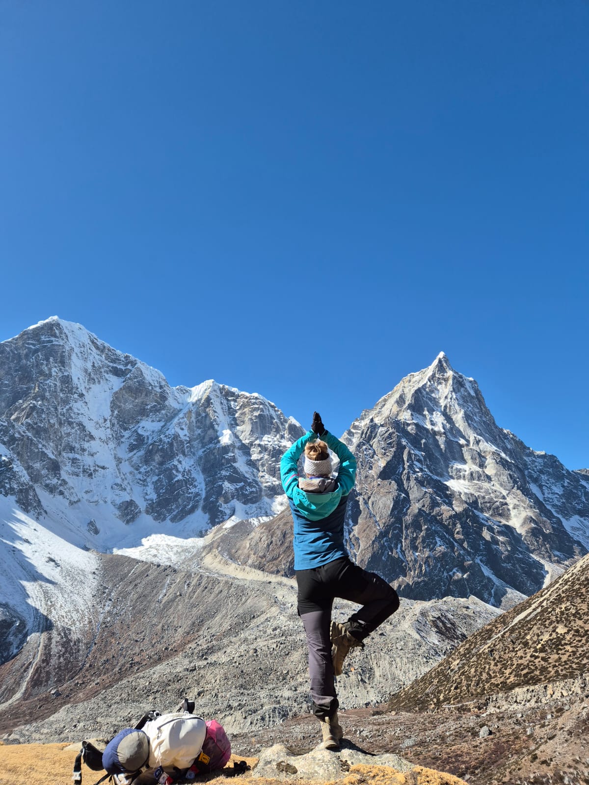 Trekkers practicing yoga outdoors near Everest Base Camp, surrounded by majestic Himalayan mountains and clear skies.