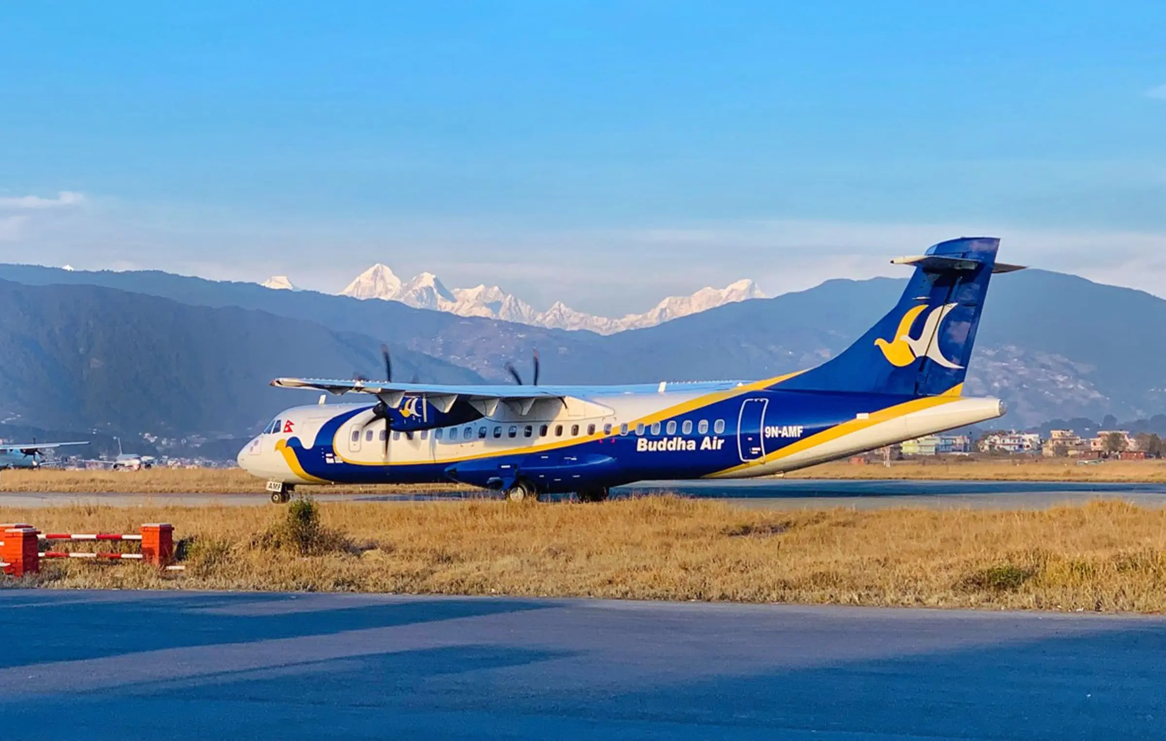 Buddha Airlines airplane landing at Pokhara Airport with mountains in the background.